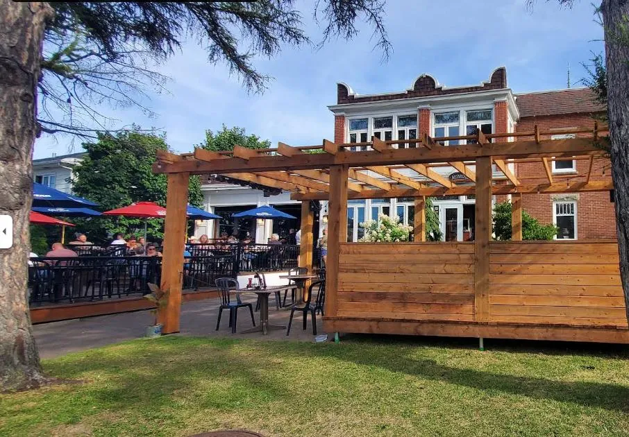 Terrasse du McBroue avec parasols devant la maison de brique centenaire